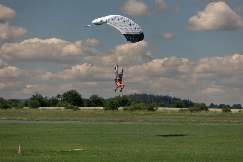 Příbram airport: landing under a white and black canopy just above the grass, forest and clouds in the background