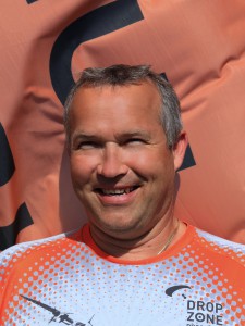 Miloš Sklenka, cámara e instructor de paracaidismo de JUMP-TANDEM, sonriente con camiseta blanca y naranja