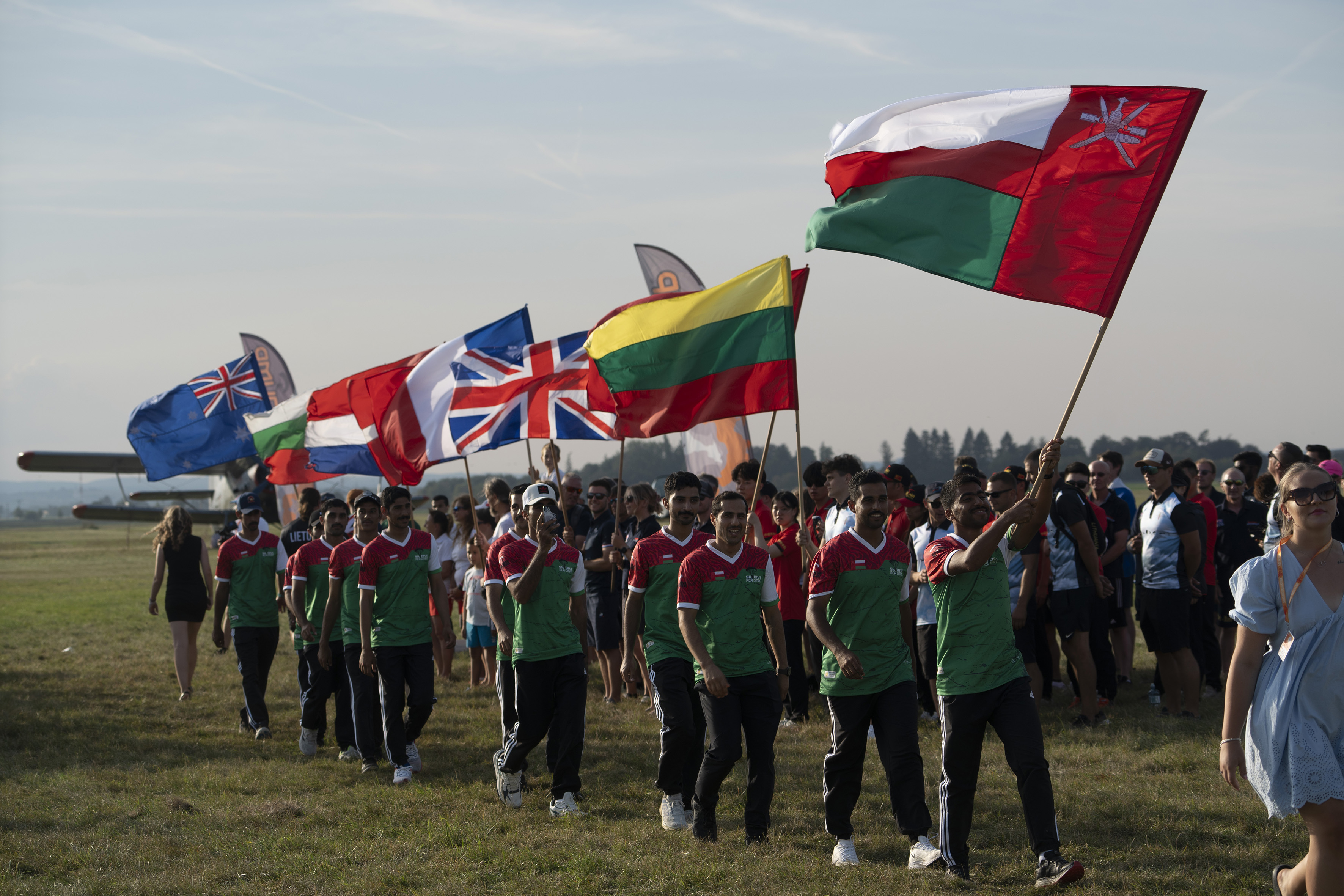 Campeonatos del Mundo FAI 2024: equipo con camisetas rojas, blancas y verdes desfila tras la bandera de Omán en el desfile de banderas