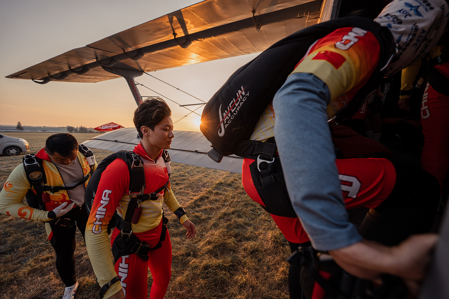 Campeonatos del Mundo FAI 2024: paracaidistas con monos rojos y amarillos con la inscripción CHINA suben al avión al atardecer
