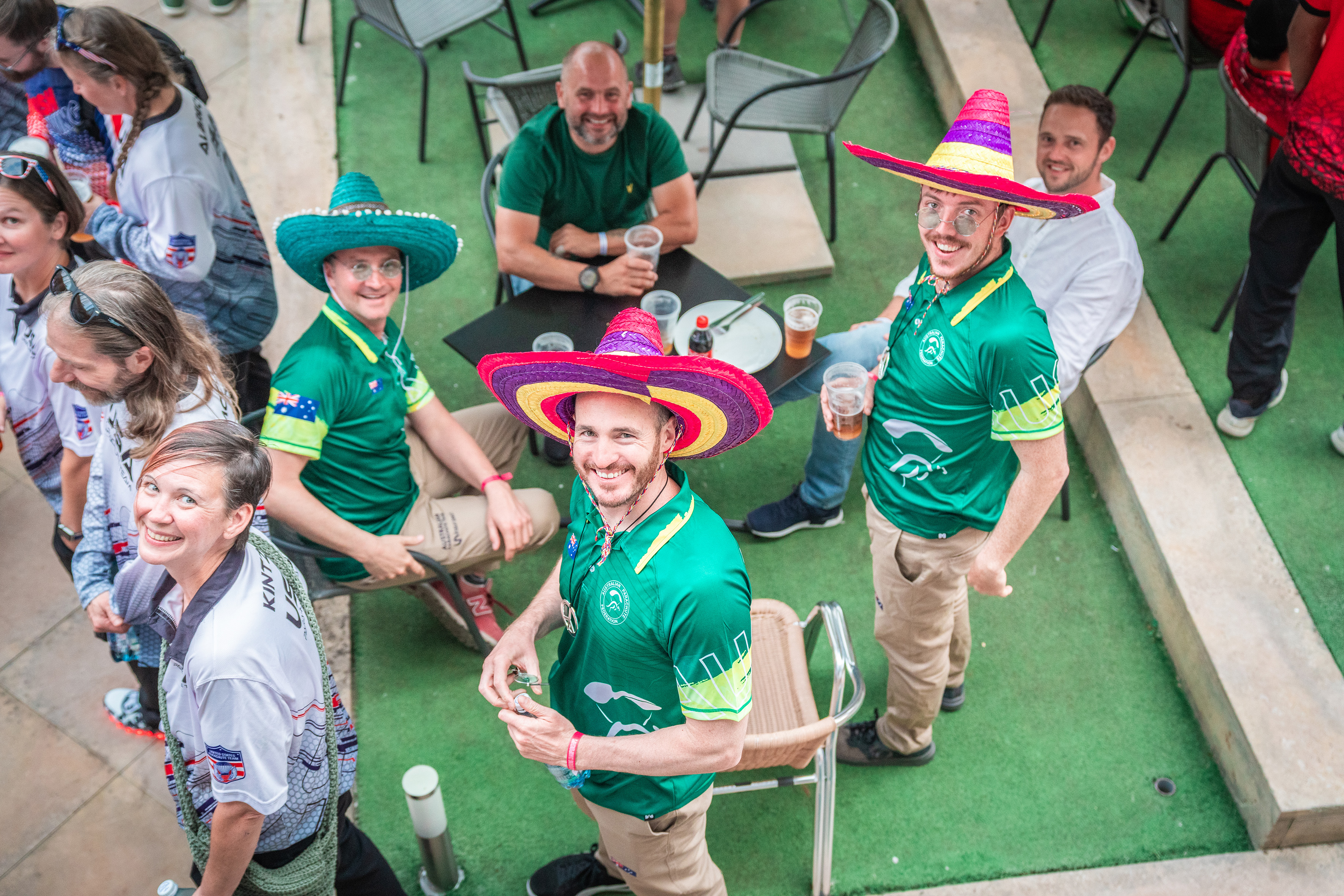Campeonatos del Mundo FAI 2024: miembros de un equipo con camisetas verdes y sombreros de colores, con cervezas, sonríen a la cámara