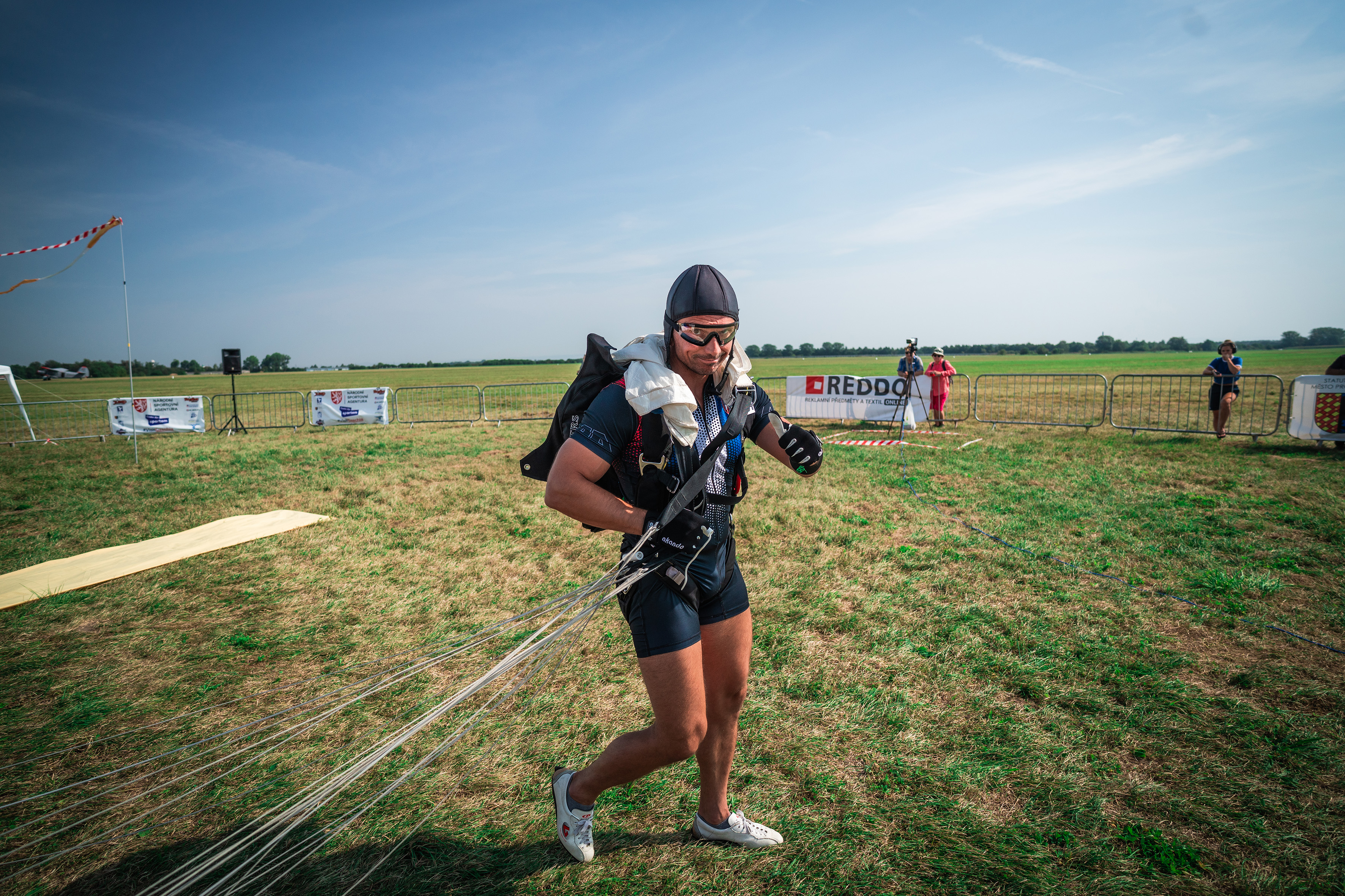 Campeonatos del Mundo FAI 2024: competidor con casco y pantalón corto camina por la hierba tras aterrizar recogiendo las cuerdas
