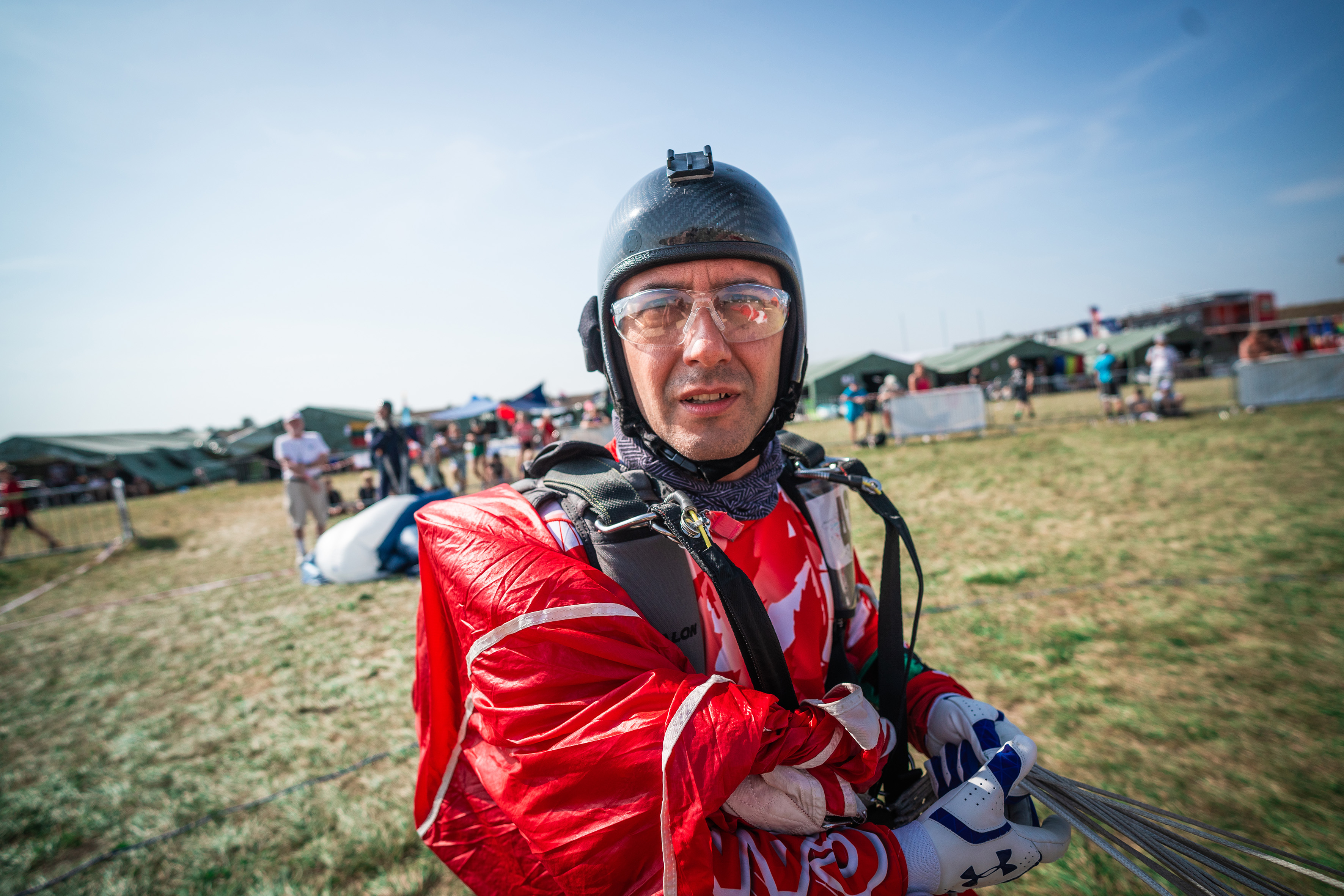 Campeonatos del Mundo FAI 2024: primer plano de un competidor con casco negro y gafas transparentes que sujeta un paracaídas rojo recogido